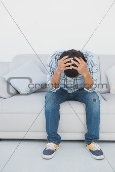Tensed football fan sitting on couch