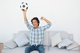 Happy soccer fan cheering while watching tv