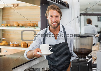 Handsome barista offering a cup of coffee to camera