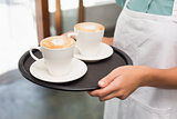 Waitress holding tray with cappuccinos