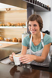 Pretty barista offering cup of coffee smiling
