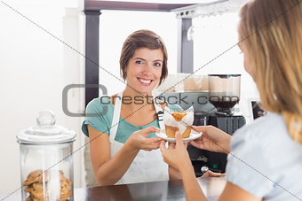 Pretty waitress serving muffin to customer
