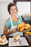 Pretty waitress showing tray of croissants