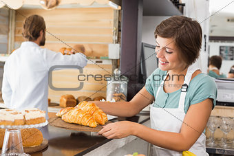 Pretty waitress holding tray of croissants