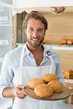 Handsome waiter holding tray of bread rolls
