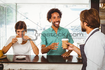 Barista serving two happy customers