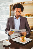 Businessman reading newspaper while having lunch