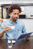 Handsome man using tablet while having coffee