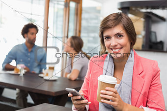 Pretty brunette sending a text drinking coffee