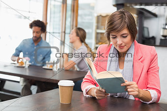 Pretty brunette enjoying her coffee with a book