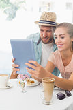 Happy couple enjoying coffee using tablet