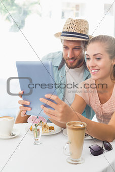 Happy couple enjoying coffee using tablet