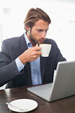 Businessman working on his laptop having coffee