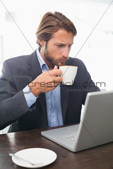 Businessman working on his laptop having coffee