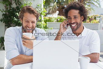 Happy friends enjoying coffee together with laptop