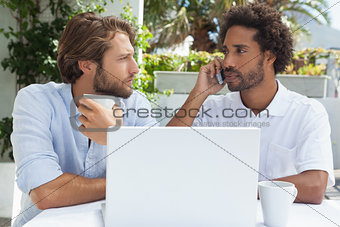 Two friends enjoying coffee together with laptop