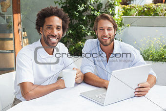 Two friends enjoying coffee together with laptop