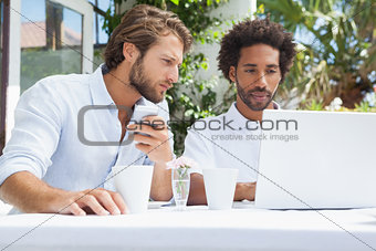 Two friends having coffee together with laptop