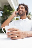 Smiling man on the phone having coffee