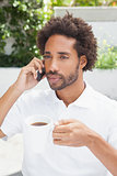 Smiling man on the phone having coffee