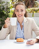 Beautiful businesswoman having a coffee and muffin