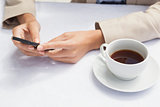 Businesswoman using smartphone with coffee