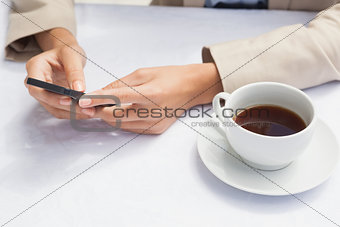 Businesswoman using smartphone with coffee