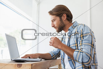 Casual man using laptop drinking espresso