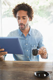 Casual man having coffee while using tablet