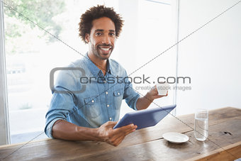 Casual man having coffee while using tablet