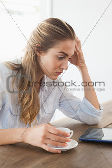 Pretty blonde having a coffee using tablet pc