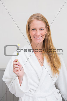 Blonde in bathrobe holding toothbrush