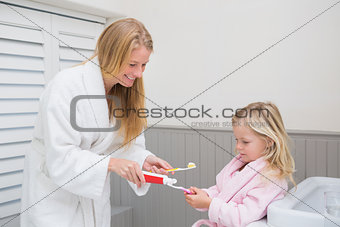 Happy mother and daughter brushing their teeth