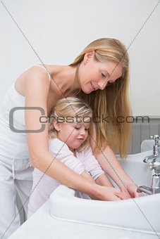 Happy mother and daughter washing hands