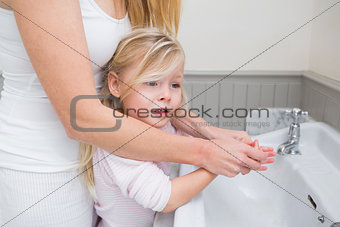 Happy mother and daughter washing hands