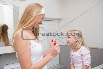Happy mother and daughter playing with make up