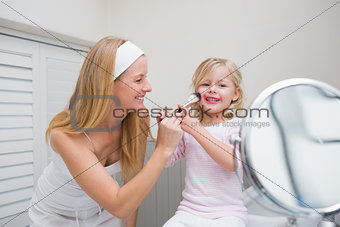 Happy mother and daughter playing with make up