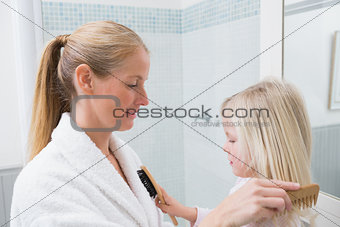 Happy mother and daughter brushing hair