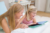 Cute little girl and mother on bed reading