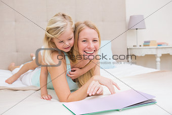 Cute little girl and mother on bed reading
