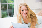 Happy blonde using tablet pc on bed