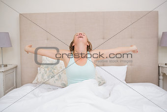 Happy blonde waking up in bed