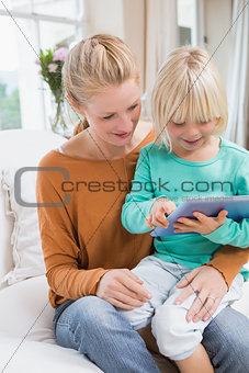 Happy mother and daughter on the couch using tablet