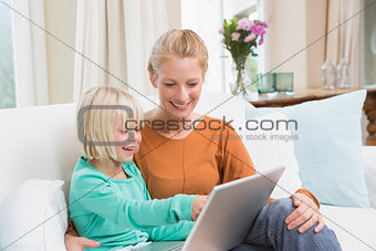 Happy mother and daughter on the couch using laptop