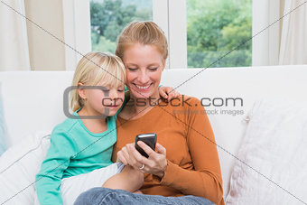 Happy mother and daughter on the couch using smartphone