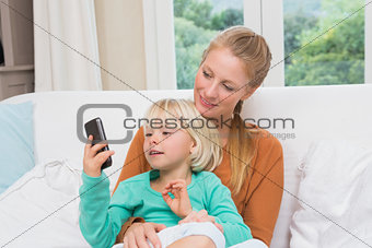 Happy mother and daughter on the couch using smartphone