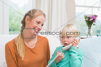 Happy mother and daughter on the couch on the phone