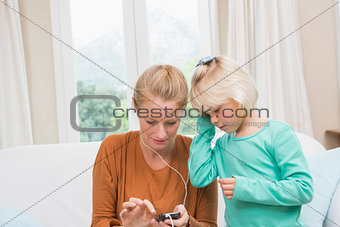 Happy mother and daughter listening to music