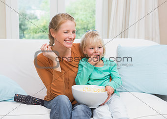 Happy mother and daughter watching tv