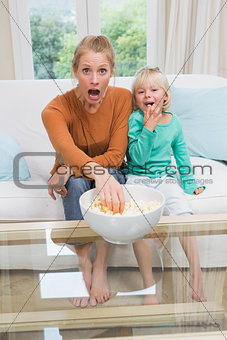 Happy mother and daughter watching tv